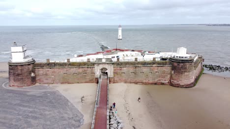 Fort-Perch-Rock-New-Brighton-lighthouse-sandstone-coastal-defence-battery-museum-aerial-view-slow-pull-back