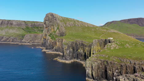 Slow-revealing-drone-shot-of-Neist-Point-lighthouse-and-rocky-shoreline-cliffs-in-Scotland