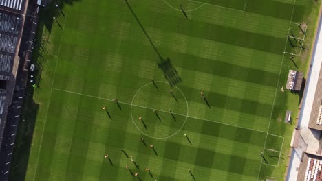 Aerial-top-down-shot-of-players-playing-soccer-game-on-field-during-sunny-day,4k