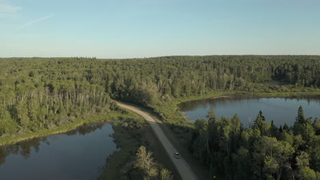 Aerial-tilt-down-over-vehicles-on-remote-road-in-Boreal-Forest,-Saskatchewan
