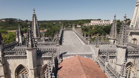 Drone-flying-over-rooftop-with-gothic-spires-of-Batalha-monastery