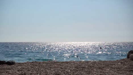 Beautiful-sparkling-ocean-horizon-with-few-peoples-swimming