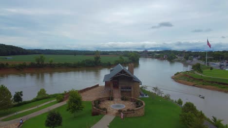 Aerial-4K-footage-with-drone-of-house-in-a-park-with-a-lake-at-the-freedom-point-marked-by-the-United-States-flag-waving-on-a-cloudy-day