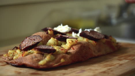 Chef-composing-a-pizza:-placing-mozzarella-on-top-of-a-potato-and-sausage-Roman-style-pizza