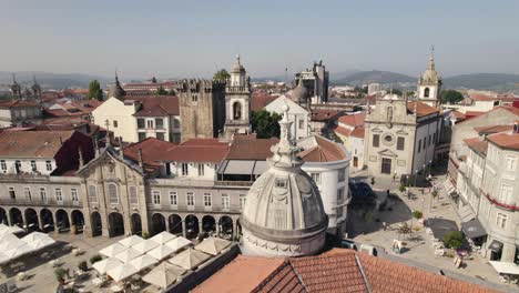 Drone-flying-low-Historic-Square-with-church-towers---Braga-Old-Downtown