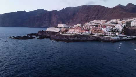 Amazing-view-Of-City-buidlings-landscape-Island-Spain-Tenerife-Los-Gigantes-Mountains-in-the-back-at-Seaside-Seashore-Water-Lagune-Drone-Shot-In-4K-Scenery