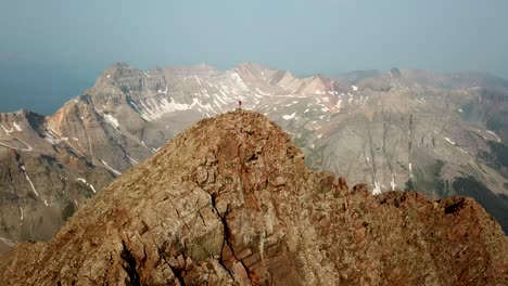 Climber-on-Top-of-Summit,-High-Above-Mountain-Range