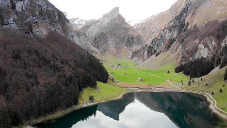 Smooth-Aerial-flyover-over-Seealpsee-in-Appenzell,-Switzerland-with-a-reflection-of-the-Alpstein-peaks-on-the-lake