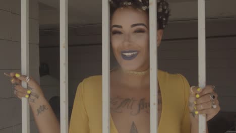 Yellow-dressed-Afro-American-Woman-behind-bars-smoking-and-looking-to-the-camera