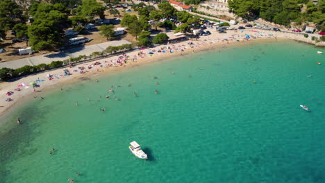 Boote-Schwimmen-Auf-Dem-Klaren-Wasser-Des-Meeres-Mit-Menschen,-Die-Sich-Am-Prapratno-Strand-In-Kroatien-Entspannen-Und-Schwimmen
