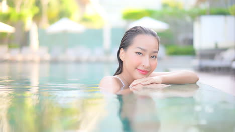 Charmante-Asiatische-Frau,-Die-Sich-Allein-Im-Pool-Entspannt-Und-In-Die-Kamera-Schaut
