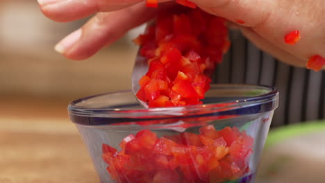 Measuring-out-a-portion-of-chopped-red-bell-peppers-for-a-homemade-recipe---isolated-slow-motion