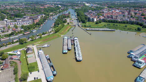 Antenne-Von-Angedockten-Frachtbooten-Mit-Einer-Schönen-Holländischen-Stadt-Im-Hintergrund