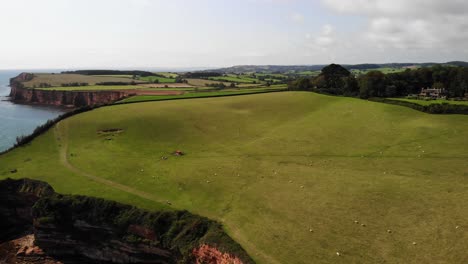 Aerial-View-Over-Rolling-Green-Idyllic-Countryside-Landscape-Beside-Devon-Coastline