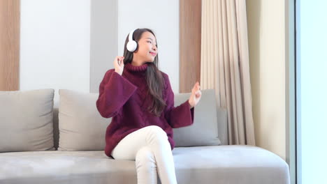 Cute-Adult-Asian-Girl-with-Headphones-Listening-to-Music-at-Home-SLOMO