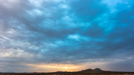Dramatic-cloudscape-at-sunrise-over-the-arid-landscape-of-the-Mojave-Desert-in-Silhouette---static-time-lapse