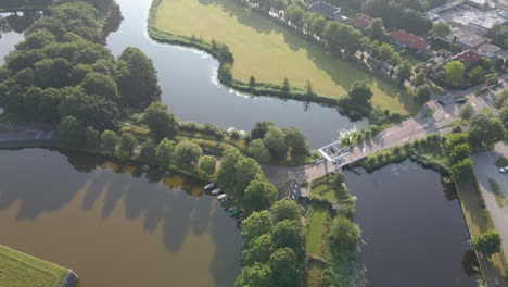 Aerial-of-white-car-passing-small-bridge-over-river-in-the-Netherlands