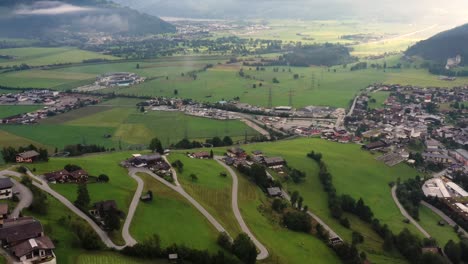 Luftaufnahmen-Der-Bergstadt-Mit-Kurviger-Straße-In-Österreich-Mit-Bunten-Häusern,-Grüner-Wiese