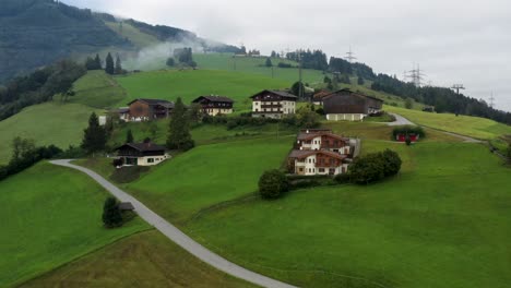 Aerial-footage-of-mountain-town-in-Austria-witha-colorful-houses,-green-meadow