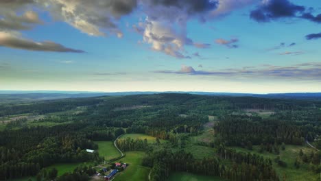Panoramic-View-Of-Countryside-Landscape-With-Coniferous-Forests,-Green-Fields,-And-Cloudy-Blue-Sky-Near-Hjo,-Sweden---aerial-shot