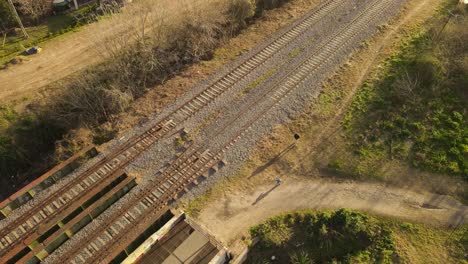AERIAL---Father-and-son-walking-next-to-railway-in-Maschwitz,-Argentina
