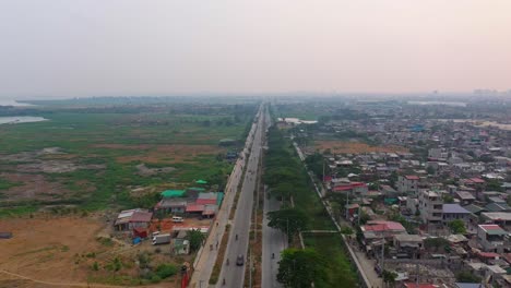 Panorama-Von-Fahrzeugen,-Die-Auf-Der-Stadtstraße-Von-Taguig-Zwischen-Wohngebiet-Und-Leerer-Landschaft-Auf-Den-Philippinen-Unterwegs-Sind