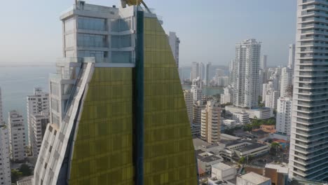 Aerial-Pedestal-Down-in-Front-of-Cartagena-Skyscraper-on-Hot-Day