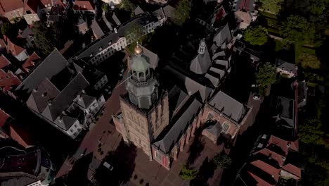 Top-down-sideways-pan-and-rotation-showing-aerial-of-Walburgiskerk-cathedral-in-medieval-Hanseatic-town-of-Zutphen-in-The-Netherlands-in-its-urban-surrounding-at-sunset