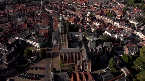 Slow-aerial-pan-above-central-square-in-medieval-Hanseatic-town-of-Zutphen,-The-Netherlands,-with-Walburgiskerk-cathedral-rising-above-and-Drogenapstoren-behind