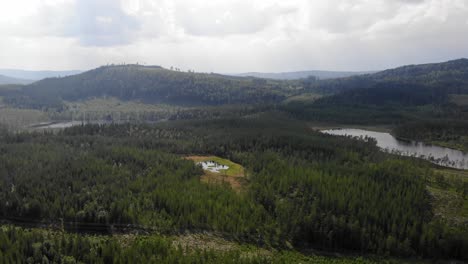 Elevated-aerial-view-of-beautiful-mountainous-arctic-nature-landscape-covered-with-coniferous-forest-with-lake-gulf-during-summer-in-Sweden