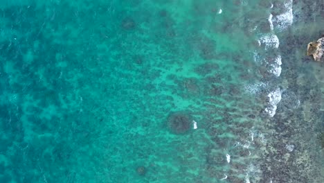 Drone-view-of-beautiful-turquiose-sea-waves-breaking-on-rocky-coastline