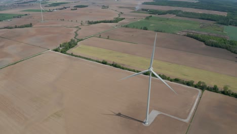 Aerial-view-of-wind-power-generation-windmills-towering-over-flat-farm-fields