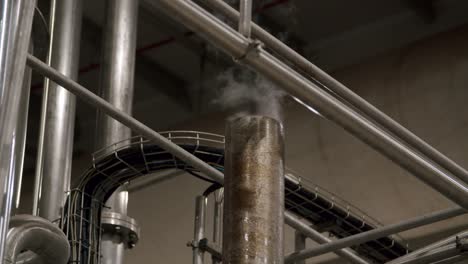 Indoor-View-Of-Metal-Chimney-In-A-Factory-With-Steam-Coming-Out---close-up
