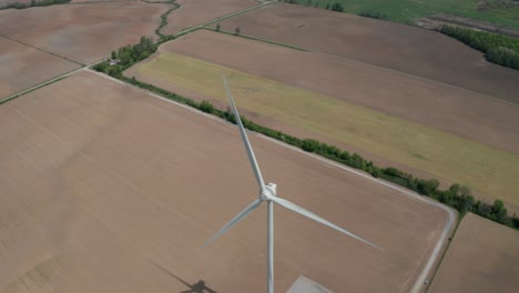 Overhead-view-of-wind-power-generation-tower-with-blades-turning-above-farm-field