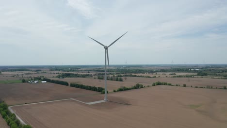 Aerial-view-from-drone-approaching-spinning-blades-of-massive-wind-power-generation-tower