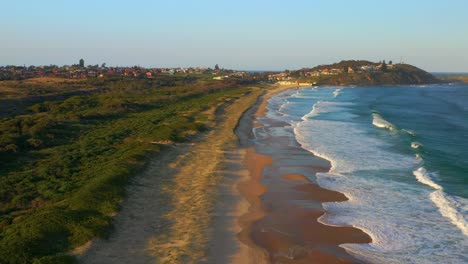 Forward-moving-aerial-shot-of-Foamy-Sea-Waves-at-Fishermans-Beach-In-Wollongong-at-sunset,-NSW,-Australia