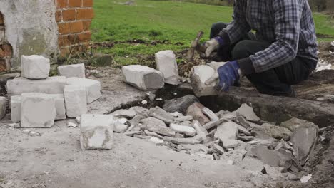 Construction-worker-removing-concrete-from-used-bricks,-static-view