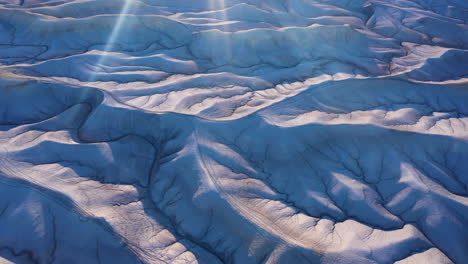 Badlands-illuminated-by-sun-rays,-Utah.-Aerial-backward