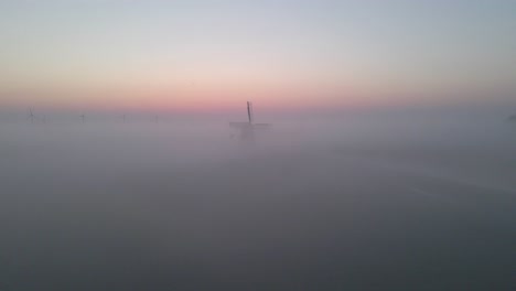 Sunrise-with-dense-fog-in-countryside-of-Holland,-iconic-windmill