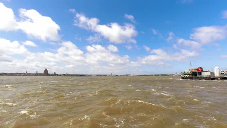 Time-lapse-windy-clouds-casting-shadows-over-River-Mersey-iconic-Snowdrop-ferry-boat-Liverpool-waterfront-pier