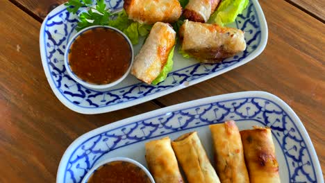 Two-plates-of-spring-rolls-with-sweet-chili-sauce-in-a-thai-restaurant,-4K-top-view