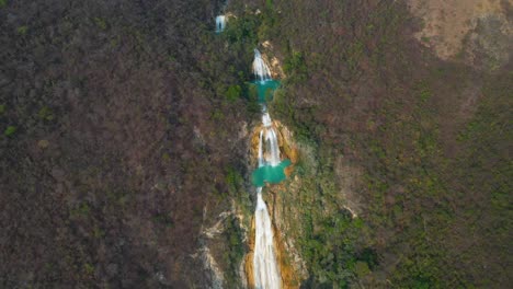 Stunning-waterfall-cascades-in-Mexico,-aerial-pull-away-reveal-background