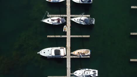 Aerial-top-down-of-yachts-and-sail-boats-with-solar-panels-moored-on-docks-in-water