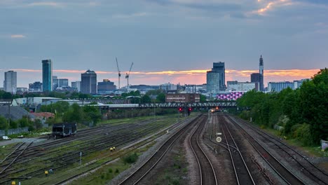 Skyline-Von-Birmingham-Bei-Sonnenuntergang-Im-Zeitraffer-Mit-Zügen,-Die-Entlang-Von-Eisenbahnlinien-In-Die-Innenstadt-Fahren