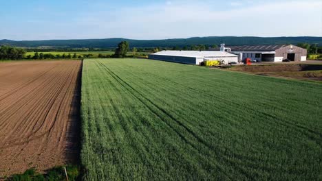 AERIAL---Farm-fields-next-to-construction-site,-Austria,-wide-spinning-shot
