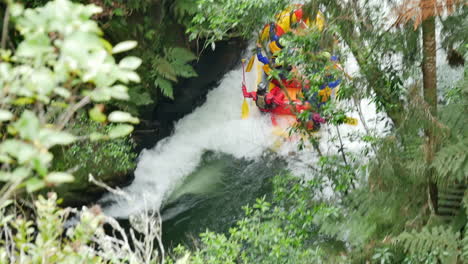 Group-of-people-in-boat-during-rafting-trip-with-kayak-surrounded-by-green-wild-nature-at-Tutea-Falls
