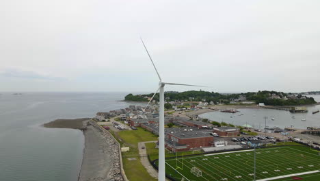 Aerial-slow-motion-reverse-footage-of-wind-turbine-and-football-field-in-Hull-MA