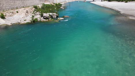 Vjosa-river-with-turquoise-water-streaming-alongside-stone-walls-of-Tepelena-city-in-Albania