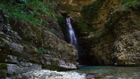Waterfall-surrounded-by-cliffs-on-a-hidden-quiet-spot-in-mountains-of-Albania,-cinematic-revealed