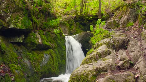 Grüne-Und-Nasse-Moosige-Steine-Und-Felsen-Entlang-Des-Bergflusses-Mit-Vielen-Geschwungenen-Kaskaden-Und-Kleinen-Wasserfällen,-Umgeben-Von-Viel-Grün-Der-Waldvegetation